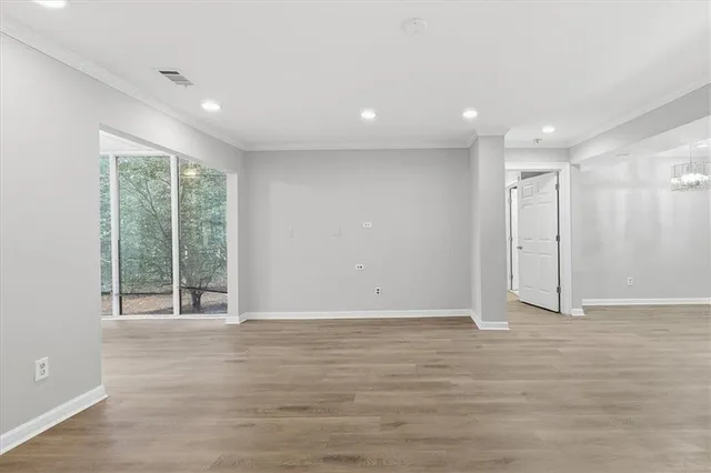 a view of a refrigerator in kitchen and an empty room with wooden floor