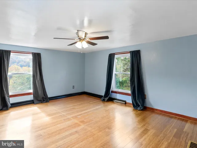 a view of an empty room with window and a chandelier fan