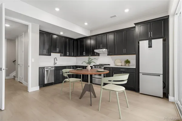 a kitchen with a refrigerator a microwave a sink and chairs