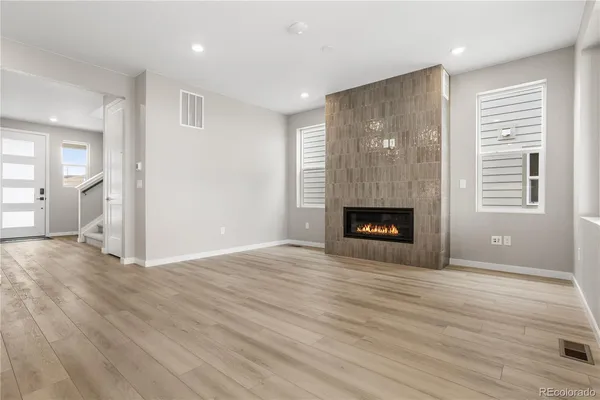 a view of an empty room with wooden floor and a fireplace