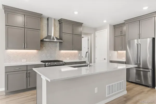 a kitchen with stainless steel appliances granite countertop a refrigerator a stove and a sink