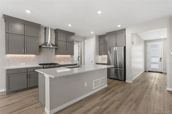 a kitchen with stainless steel appliances granite countertop a stove a refrigerator and a sink with wooden floor