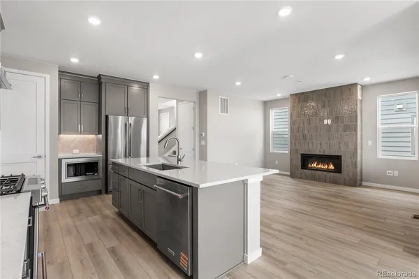 a kitchen with stainless steel appliances granite countertop a stove refrigerator and a fireplace