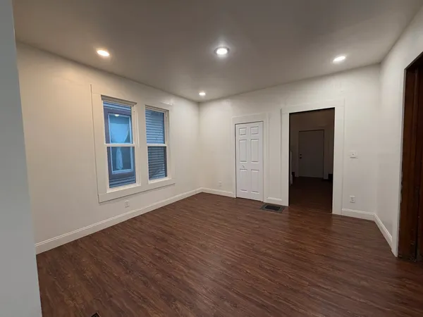 a view of empty room with wooden floor and fan