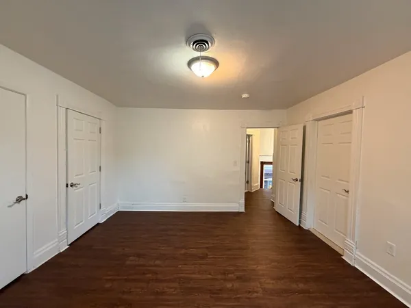 a view of an empty room with wooden floor and closet