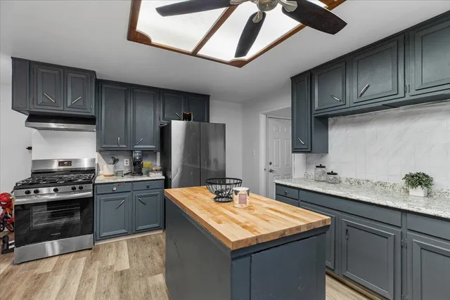 a kitchen with stainless steel appliances granite countertop a sink a stove and wooden floors