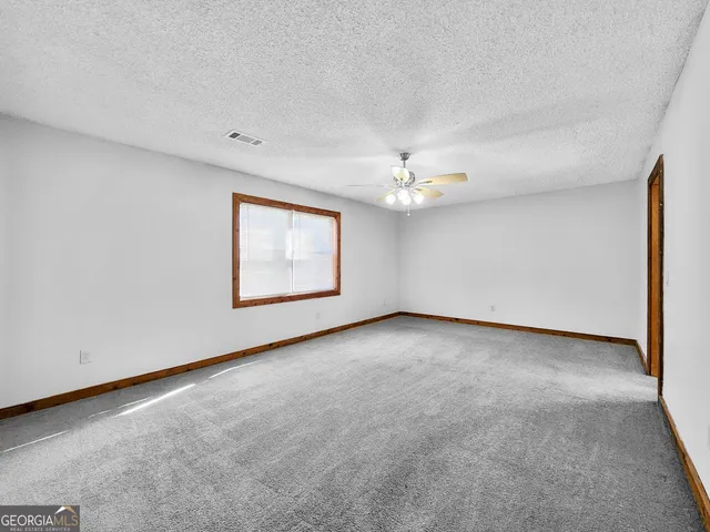 an empty room with a chandelier fan and windows