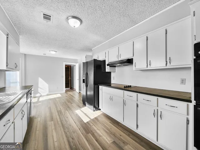 a kitchen with granite countertop white cabinets and stainless steel appliances