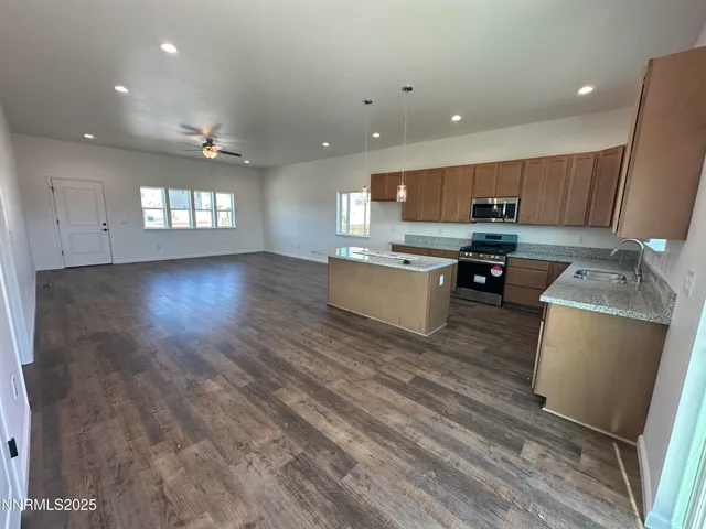 a kitchen with a sink stainless steel appliances wooden floor and a window