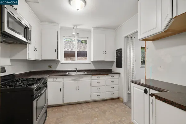 a kitchen with granite countertop white cabinets and stainless steel appliances