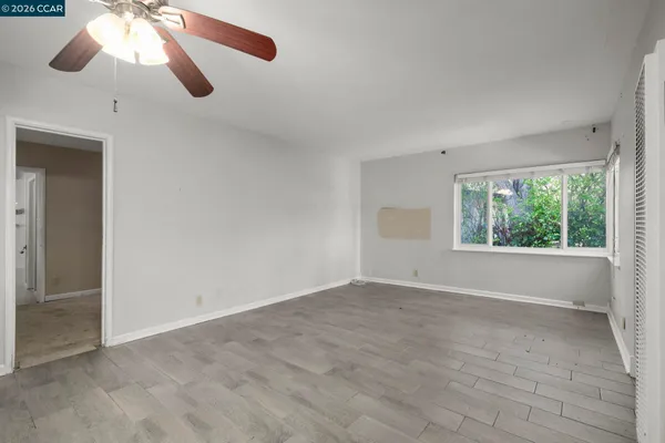 a view of empty room with wooden floor and fan