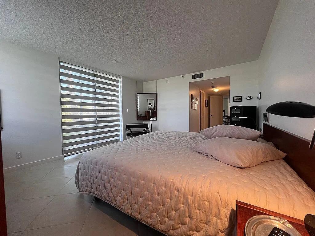 6463 La Costa Drive, Unit 105 Boca Raton, FL 33433 - Photo 28 of 40 a bedroom with a large bed and a chandelier