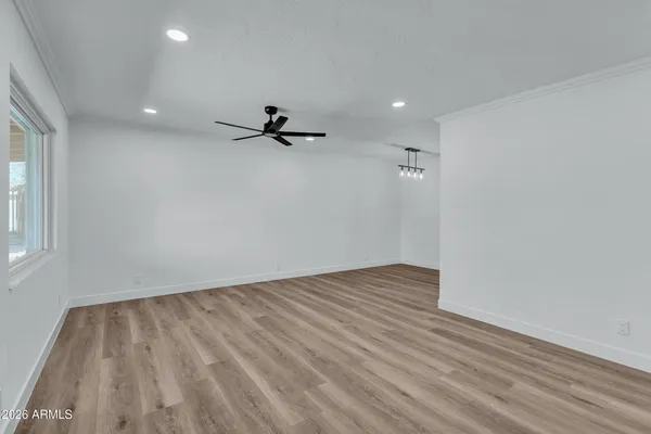 a view of empty room with wooden floor and fan