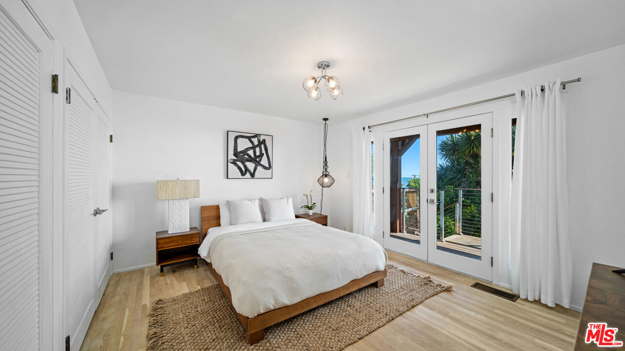 21344 Rambla Vista Malibu, CA 90265 - Photo 16 of 32 a bedroom with a large bed and a chandelier