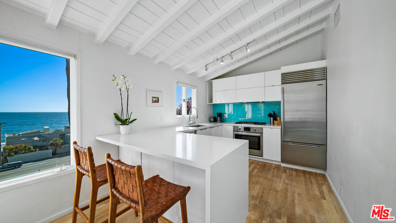 21344 Rambla Vista Malibu, CA 90265 - Photo 10 of 32 a kitchen with stainless steel appliances kitchen island granite countertop a refrigerator and a stove top oven