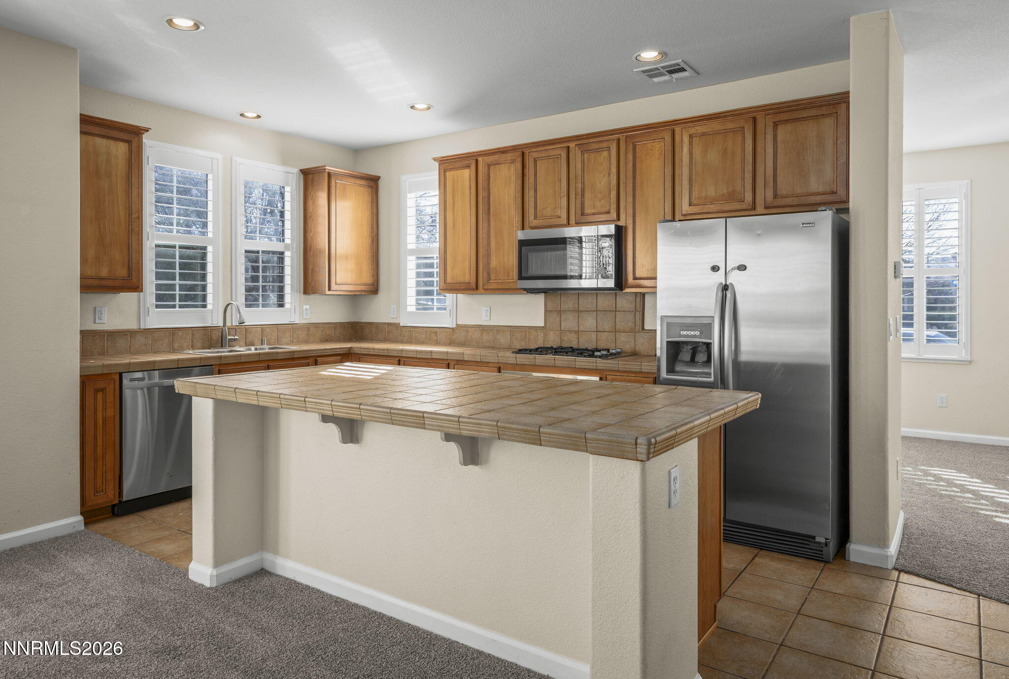 6953 Sacred Circle Sparks, NV 89436 - Photo 6 of 26 a kitchen with kitchen island granite countertop a stove refrigerator and microwave