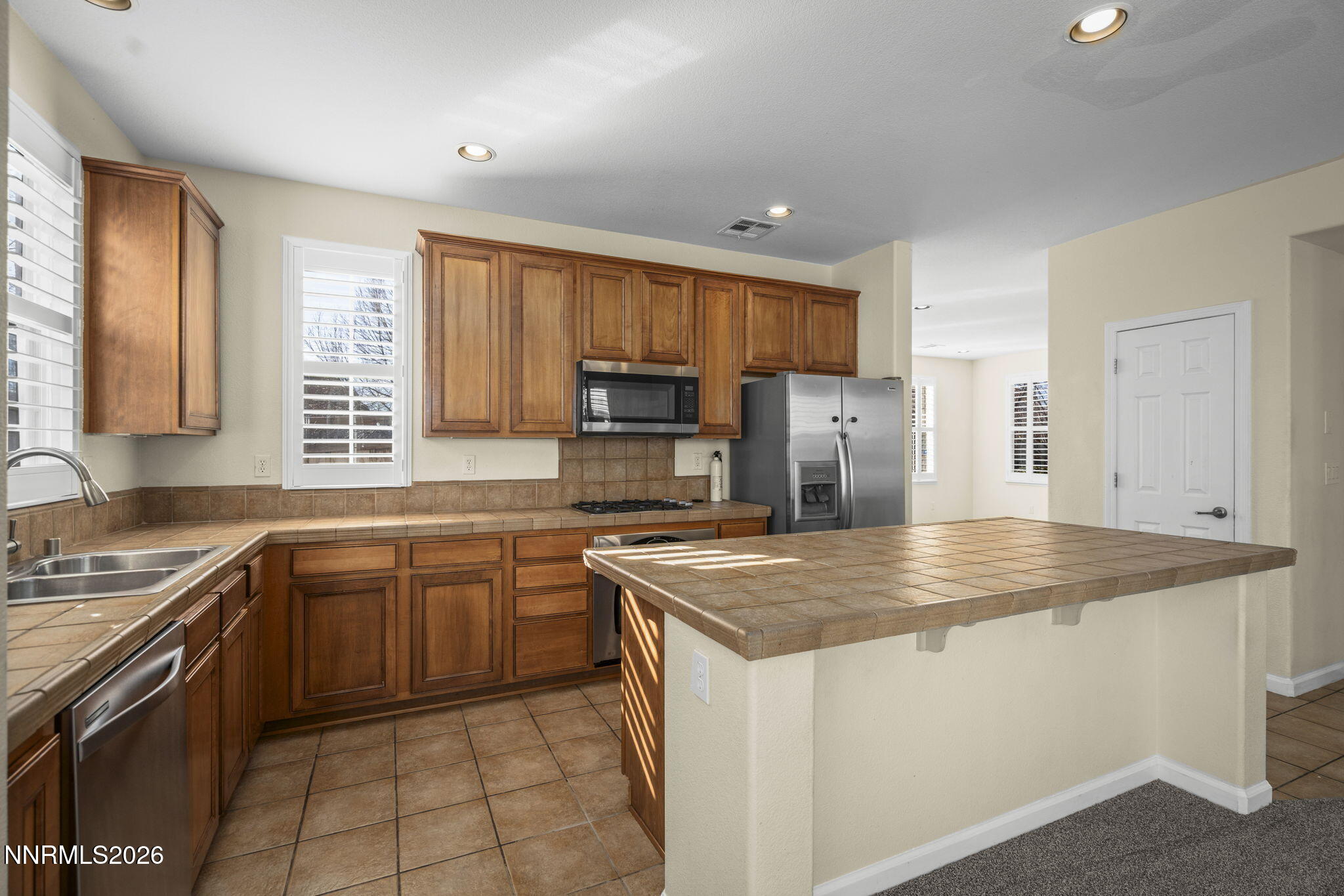 6953 Sacred Circle Sparks, NV 89436 - Photo 7 of 26 a kitchen with stainless steel appliances granite countertop a sink stove microwave and refrigerator