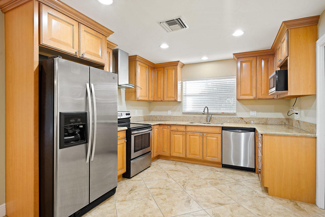 4572 White Cedar Lane Delray Beach, FL 33445 - Photo 7 of 37 a kitchen with granite countertop stainless steel appliances a refrigerator sink stove microwave and cabinets