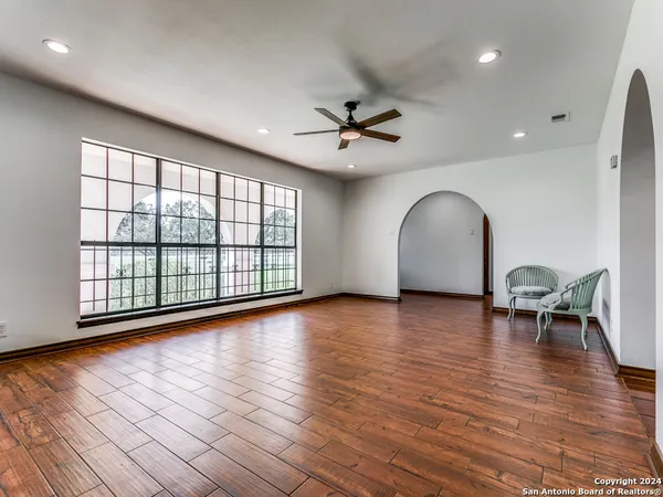 a view of empty room with wooden floor and fan