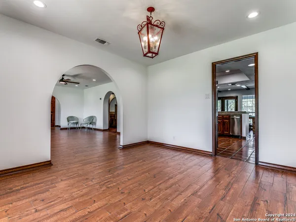 a hallway with wooden floor chandelier and a window