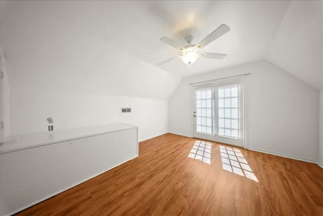 an empty room with wooden floor fan and windows