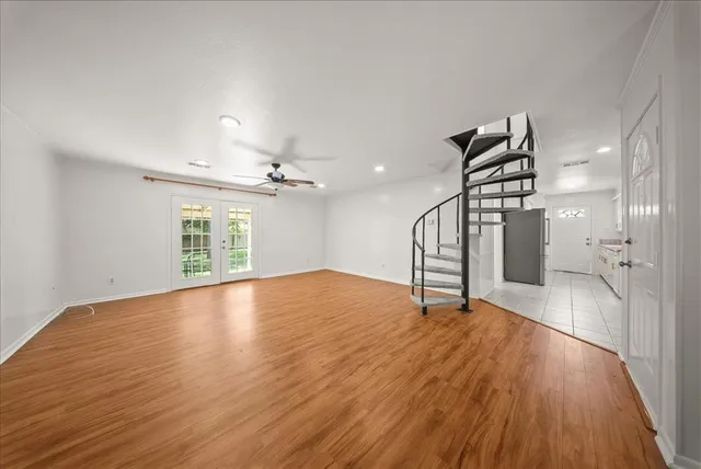 a view of empty room with wooden floor and ceiling fan
