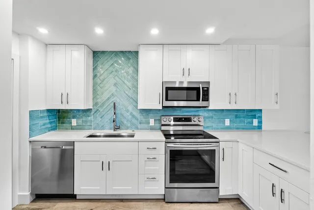 a kitchen with white cabinets and stainless steel appliances