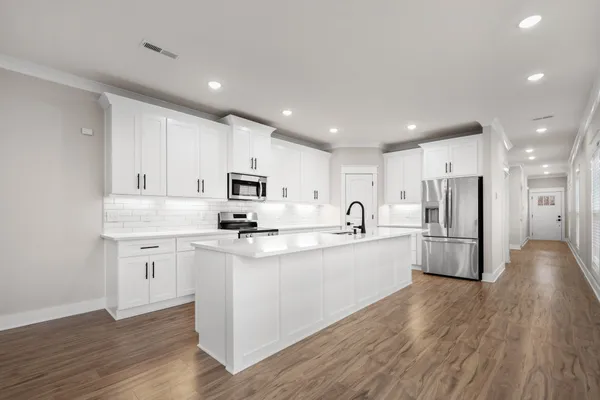 a kitchen with stainless steel appliances a refrigerator sink and white cabinets
