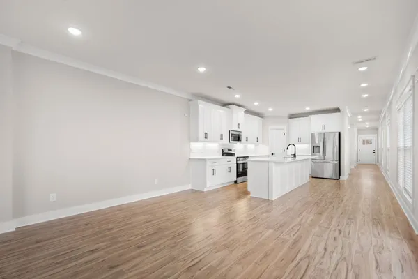 a large white kitchen with stainless steel appliances granite countertop a large counter top and a wooden floors
