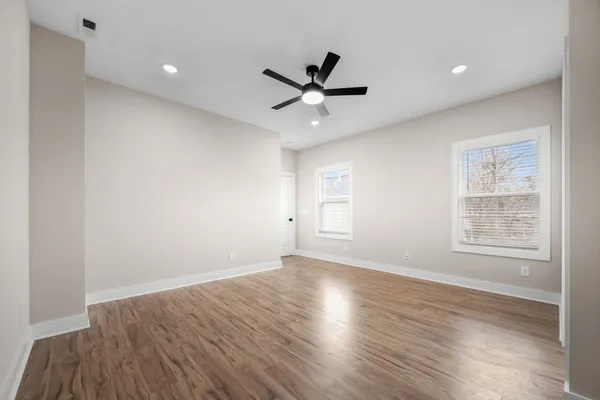 a view of an empty room with wooden floor and a window