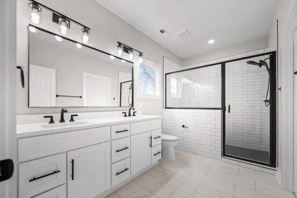 a bathroom with a double vanity sink toilet mirror and shower