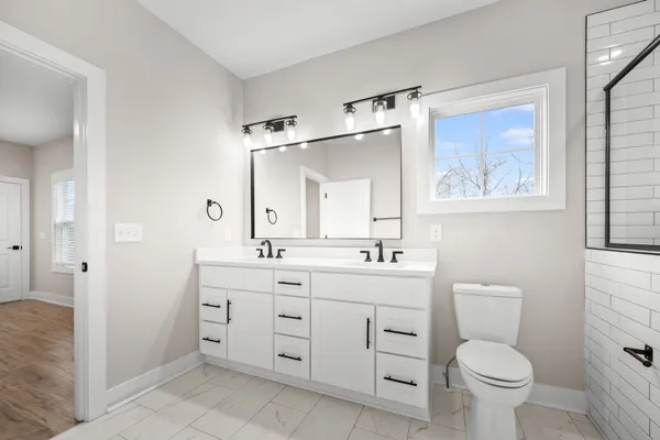 a bathroom with a double vanity sink toilet and a mirror