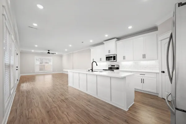 a open kitchen with white cabinets wooden floor and stainless steel appliances