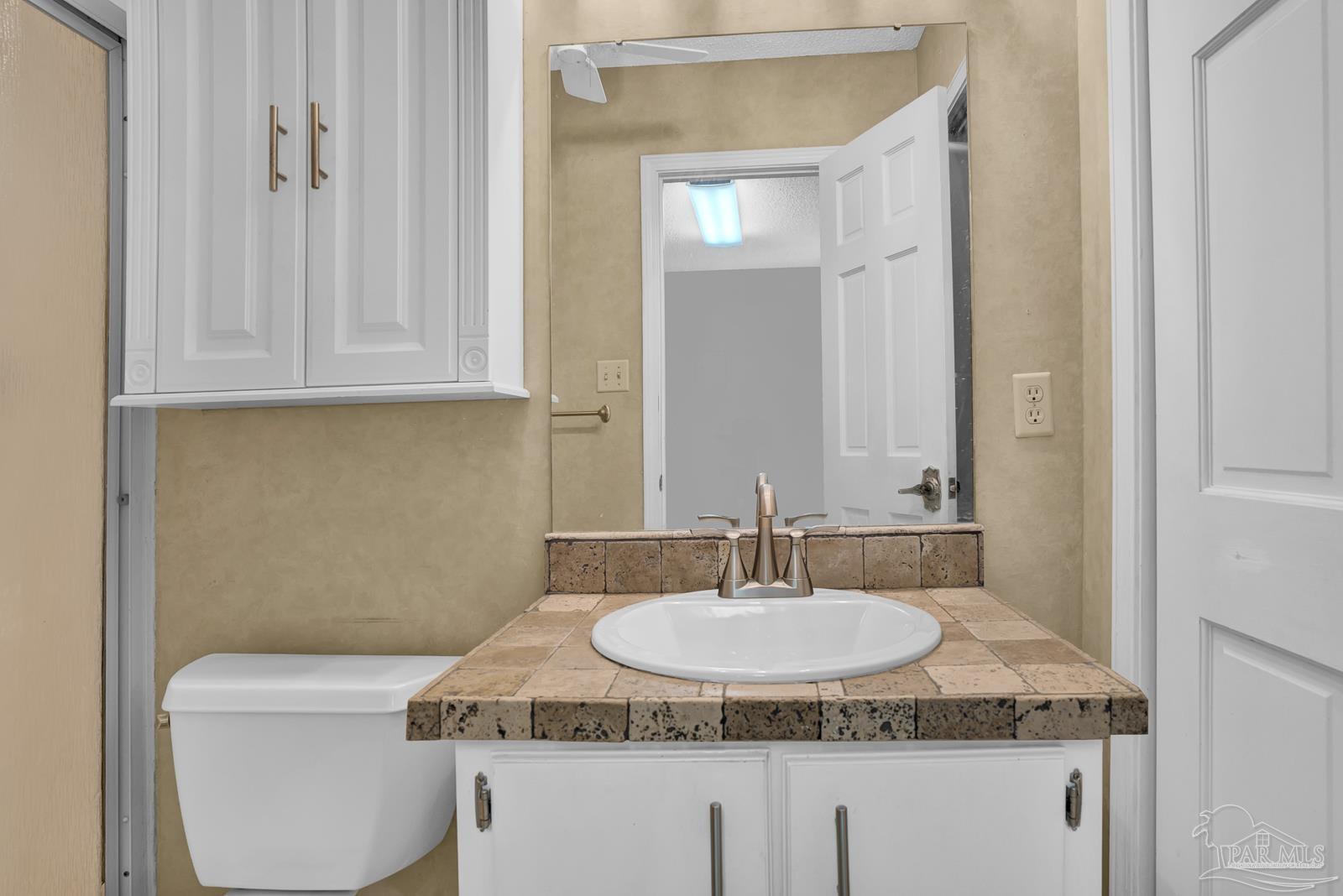 5036 Hamilton Lane Pace, FL 32571 - Photo 12 of 37 a bathroom with a granite countertop sink a toilet and mirror