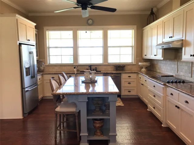 a kitchen with granite countertop a stove a sink and a refrigerator