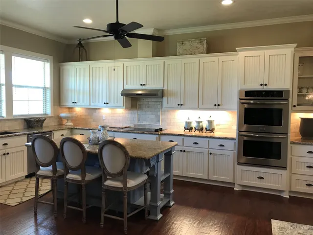 a kitchen with granite countertop white cabinets and stainless steel appliances