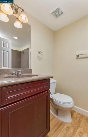 a bathroom with a granite countertop toilet sink and mirror