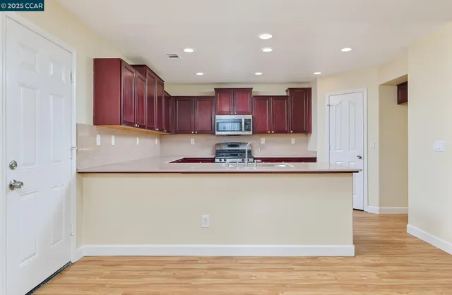 a kitchen with stainless steel appliances granite countertop a stove a refrigerator and a microwave with wooden floors