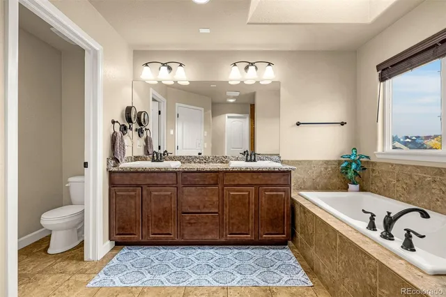 a bathroom with a granite countertop tub a double vanity sink and a mirror