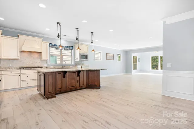 a large kitchen with stainless steel appliances kitchen island granite countertop a stove a sink and white cabinets