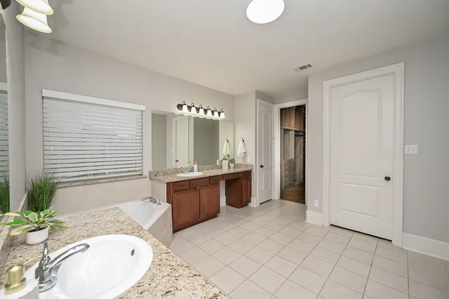 a spacious bathroom with a granite countertop tub sink and mirror