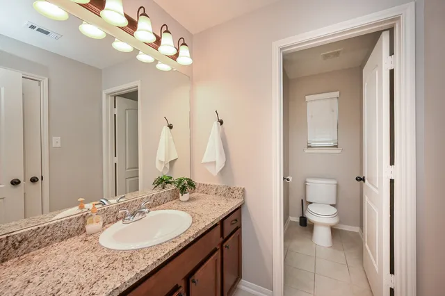 a bathroom with a granite countertop sink a toilet and a mirror