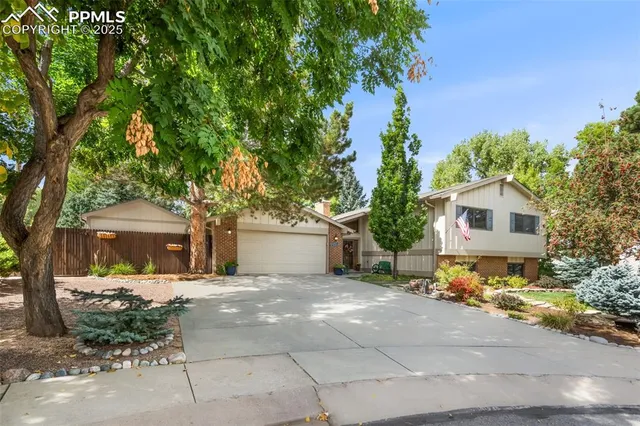 a front view of a house with a garden and tree
