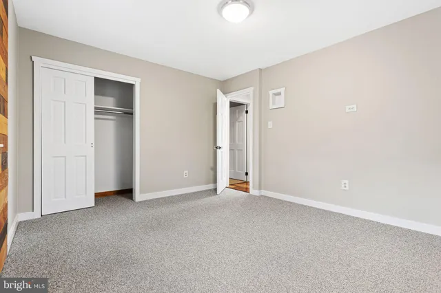 a view of an empty room with closet and a window