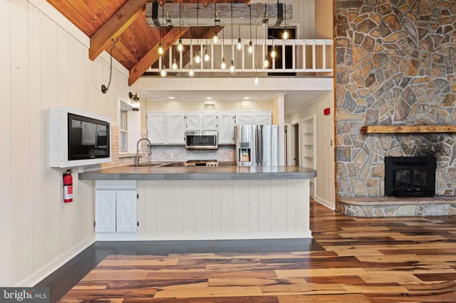 a view of living room kitchen with stainless steel appliances granite countertop furniture and flat screen tv