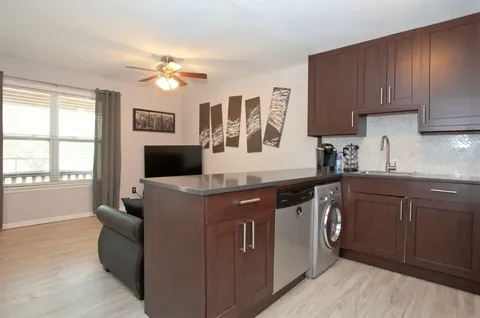 a kitchen with stainless steel appliances granite countertop a sink and dishwasher a stove top oven with wooden floor