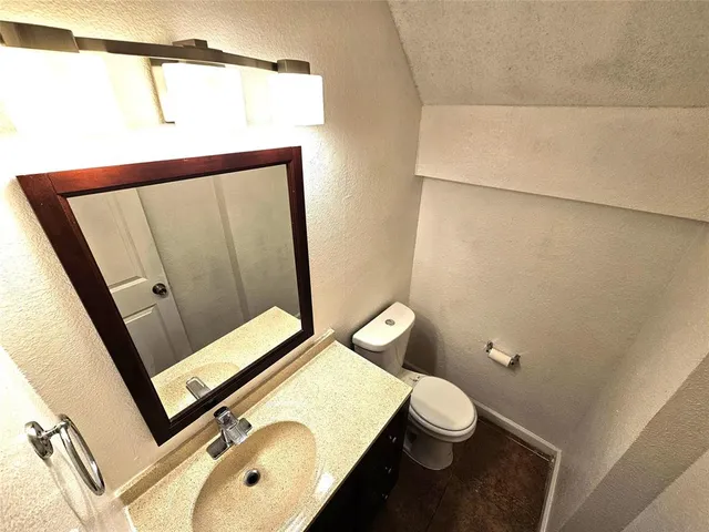 a bathroom with a toilet sink vanity and mirror