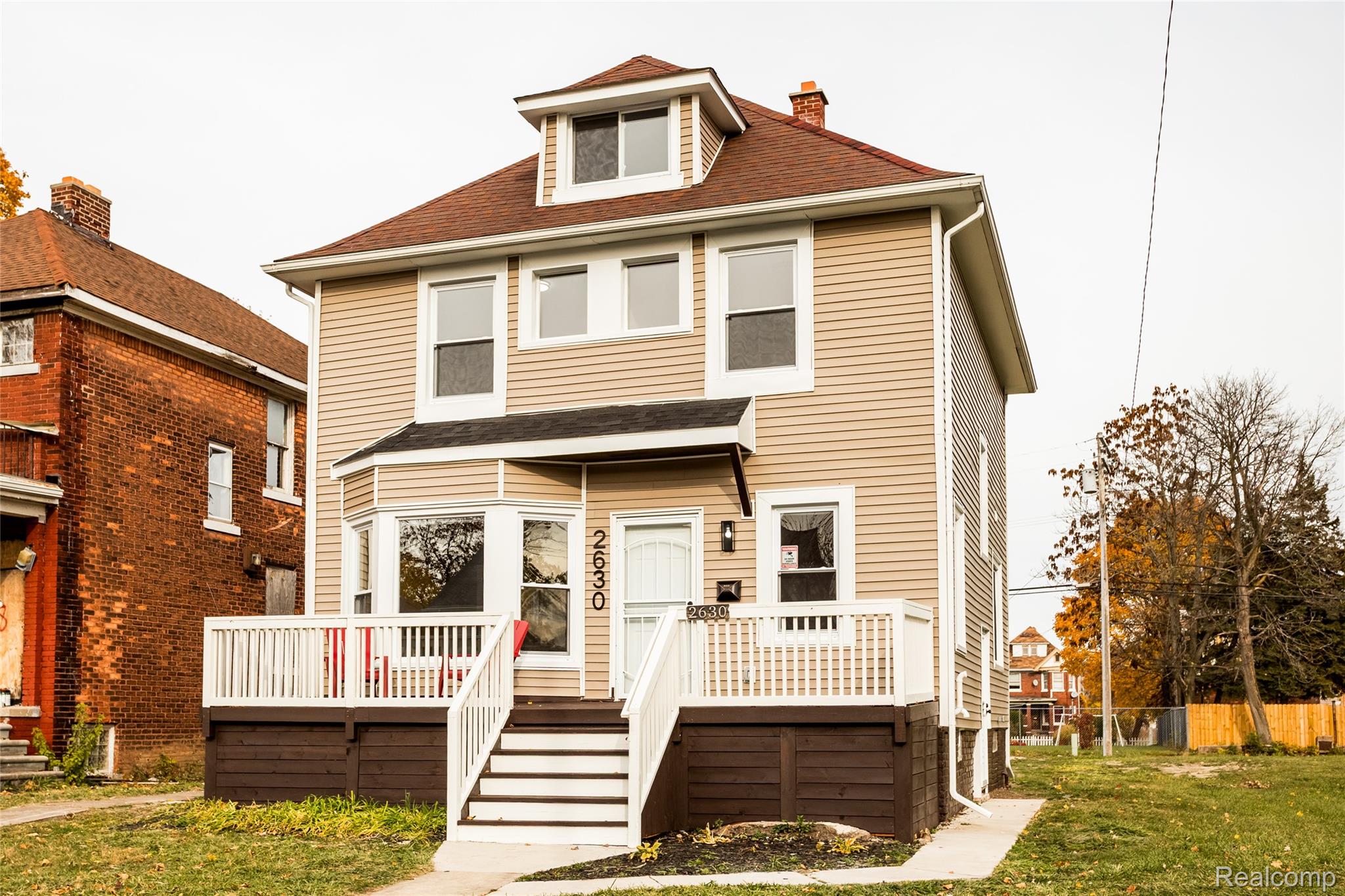 Two-story residence featuring light beige siding, a red shingle roof, and a prominent front bay window