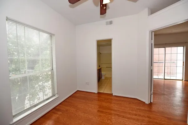 a view of an empty room with window and wooden floor
