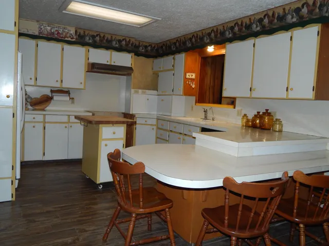 a kitchen with stainless steel appliances a dining table chairs and sink